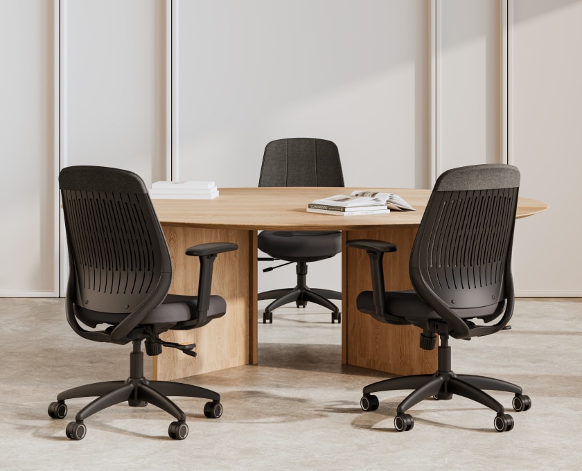 Three ErgoStretch office chairs around a wooden conference table in a modern meeting room.